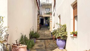 A narrow stone-paved alleyway flanked by buildings with potted plants and a staircase leading to an upper level. - Dinas Apartment - Alonnisos Summer Haven (Alonissos)