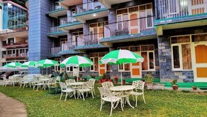 A courtyard with outdoor seating and potted plants. - Gagan Resort (Dharamshala)