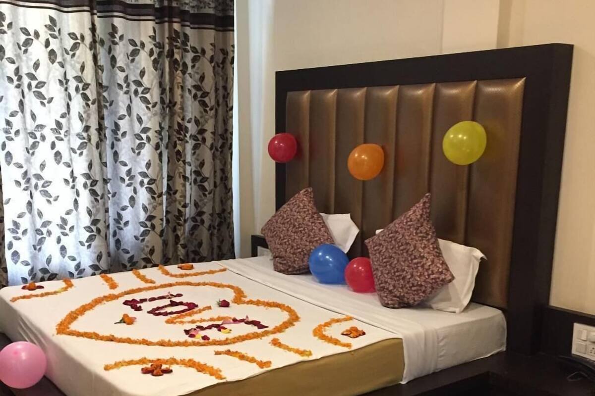 A neatly made bed with a floral bedspread, pillows, and balloons.