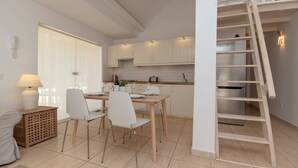 A modern kitchen with white cabinets, a dining table with chairs, and a wooden ladder leading to an upper level. - Palms 4 - Three Bed S (Golf del Sur)