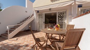 A patio with a round wooden table, chairs, and a staircase leading to an upper level. - Palms 4 - Three Bed S (Golf del Sur)