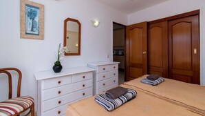 Une chambre à coucher comprenant un lit, une commode, une chaise, un miroir et une armoire.