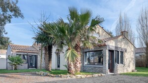A modern house with a stone facade, large windows, and a gravel driveway. - House with an extension for 11 at 800m from the sea (La Plaine-sur-Mer)