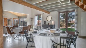 A dining area with a round table set for six, surrounded by chairs. There is a fireplace with a mirror above it, and large windows providing a view of the outdoors. - House with an extension for 11 at 800m from the sea (La Plaine-sur-Mer)