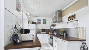 A modern kitchen with white cabinets, stainless steel appliances, and a wooden countertop.