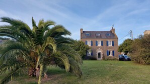 A two-story house with a well-maintained lawn and a large palm tree in the foreground.