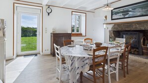 A dining area with a round table, chairs, a clock, and a fireplace.