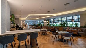 Enjoy a meal in a stylish restaurant with bar stools, round tables, and cozy seating areas.