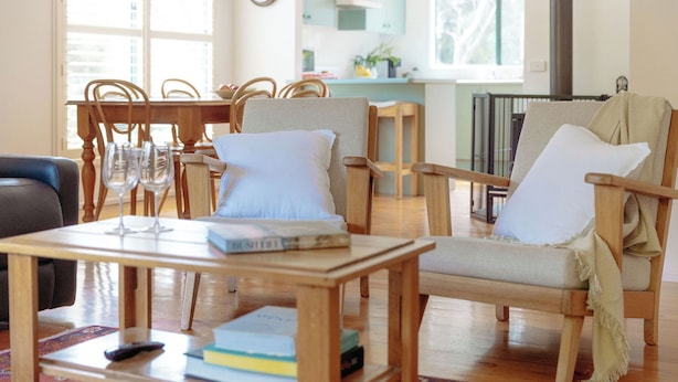 Un salón acogedor con una mesa de centro de madera, dos sillones y un comedor con una mesa y sillas de madera.