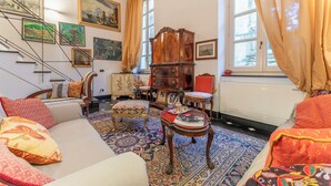 A room with a sofa, ottoman, wooden cabinet, and a patterned rug. - Portello Apartment By Geco Vacation Rentals (Genoa)