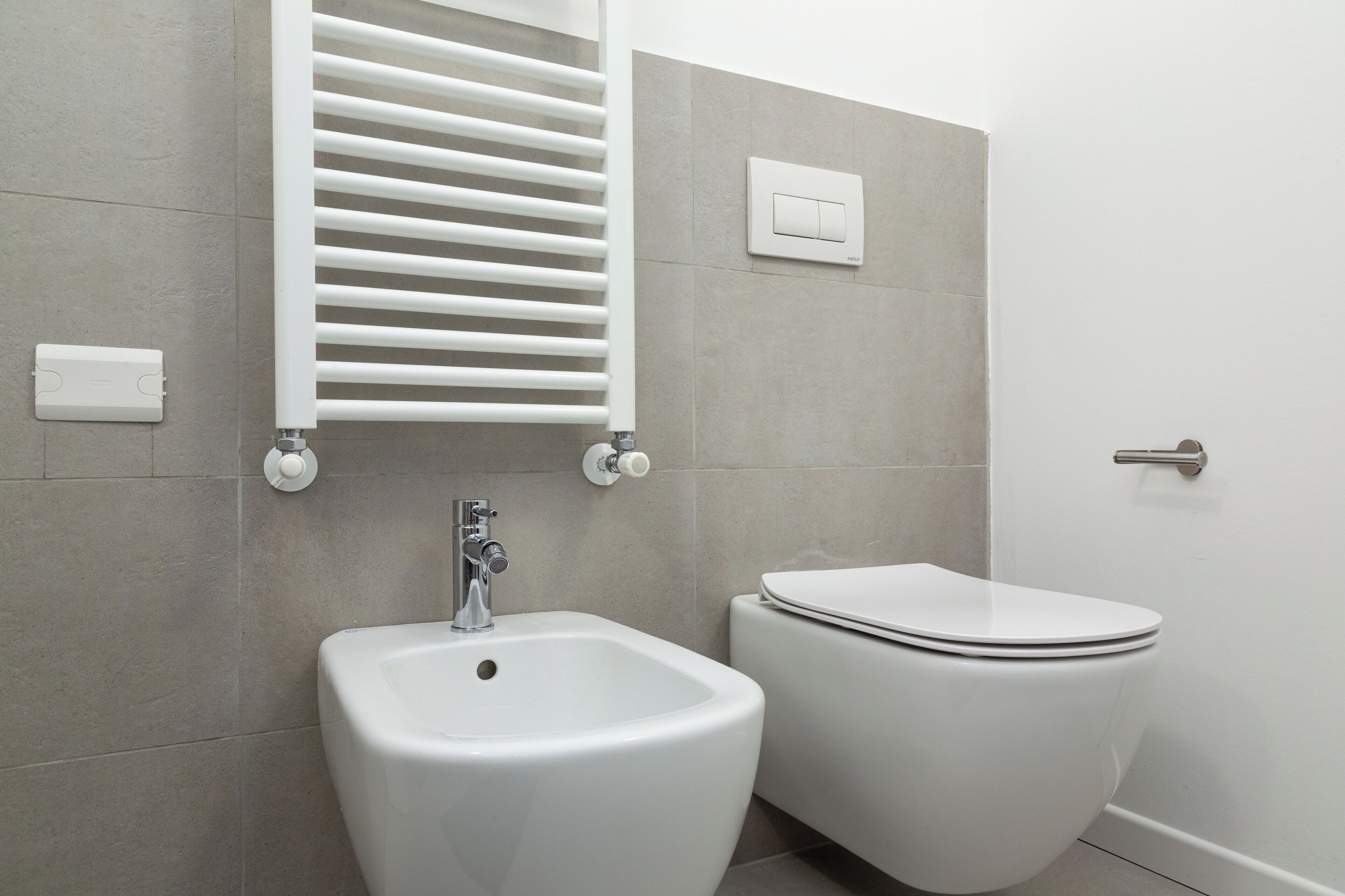 A modern bathroom with a bidet, toilet, and a towel rack.