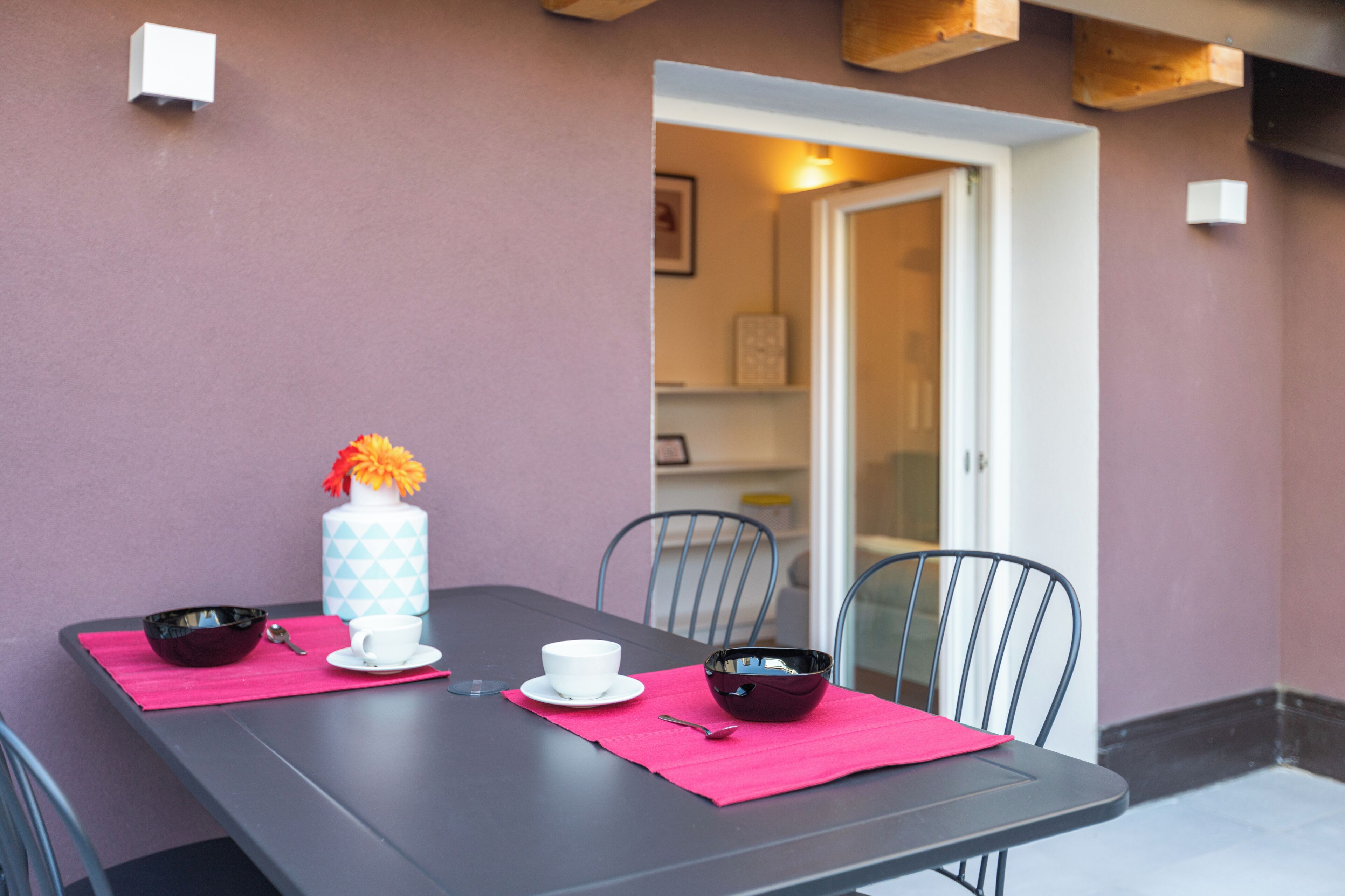A table with a white cup, a black bowl, and a blue vase with flowers.