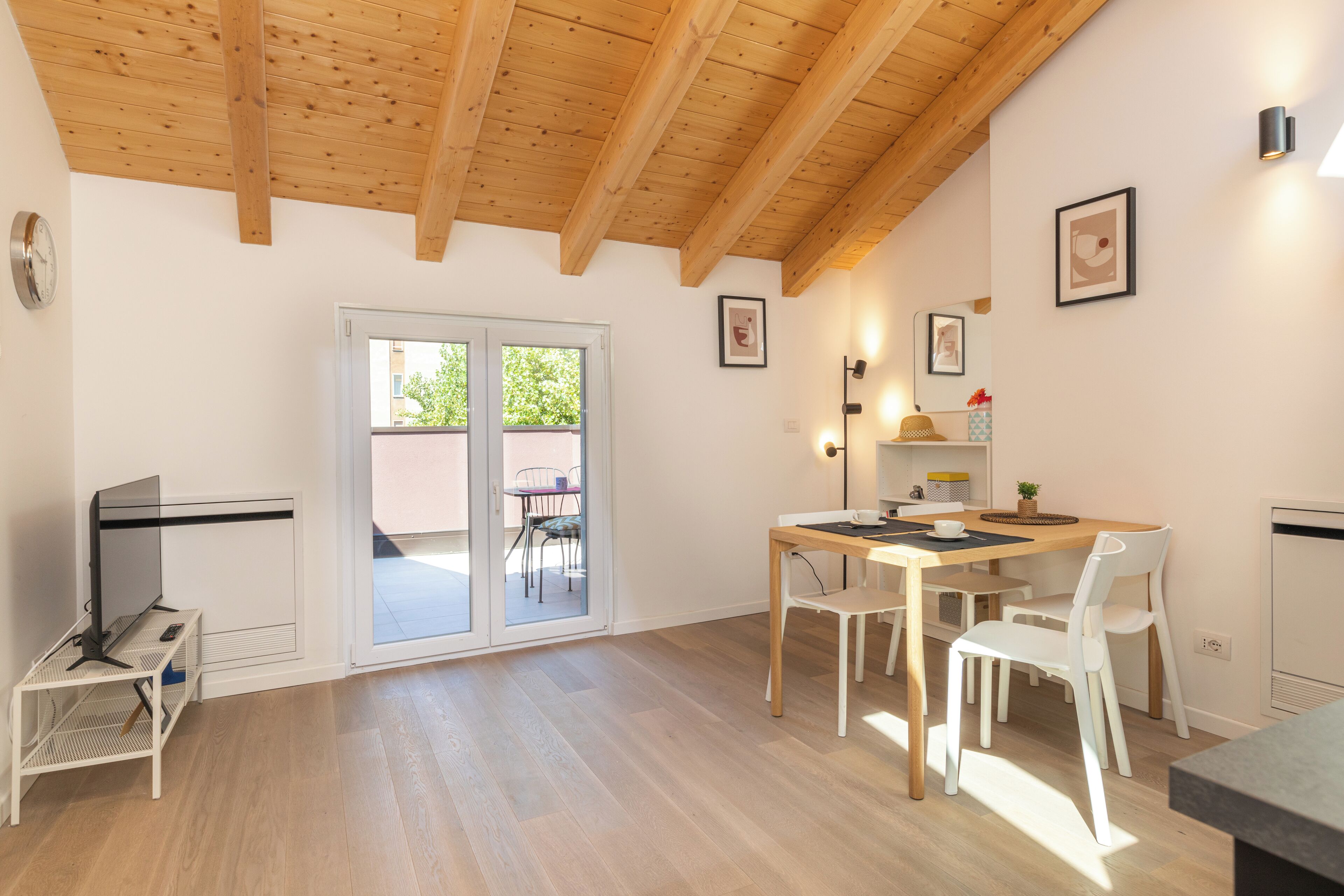 Una cocina moderna con vigas de madera, una mesa de comedor con sillas y un vidrio corredero que da a un espacio exterior.