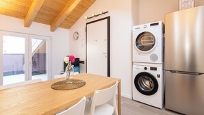 A compact kitchen with a wooden table, a washing machine, and a refrigerator. - JOIVY Contemporary Apartments (Milan)