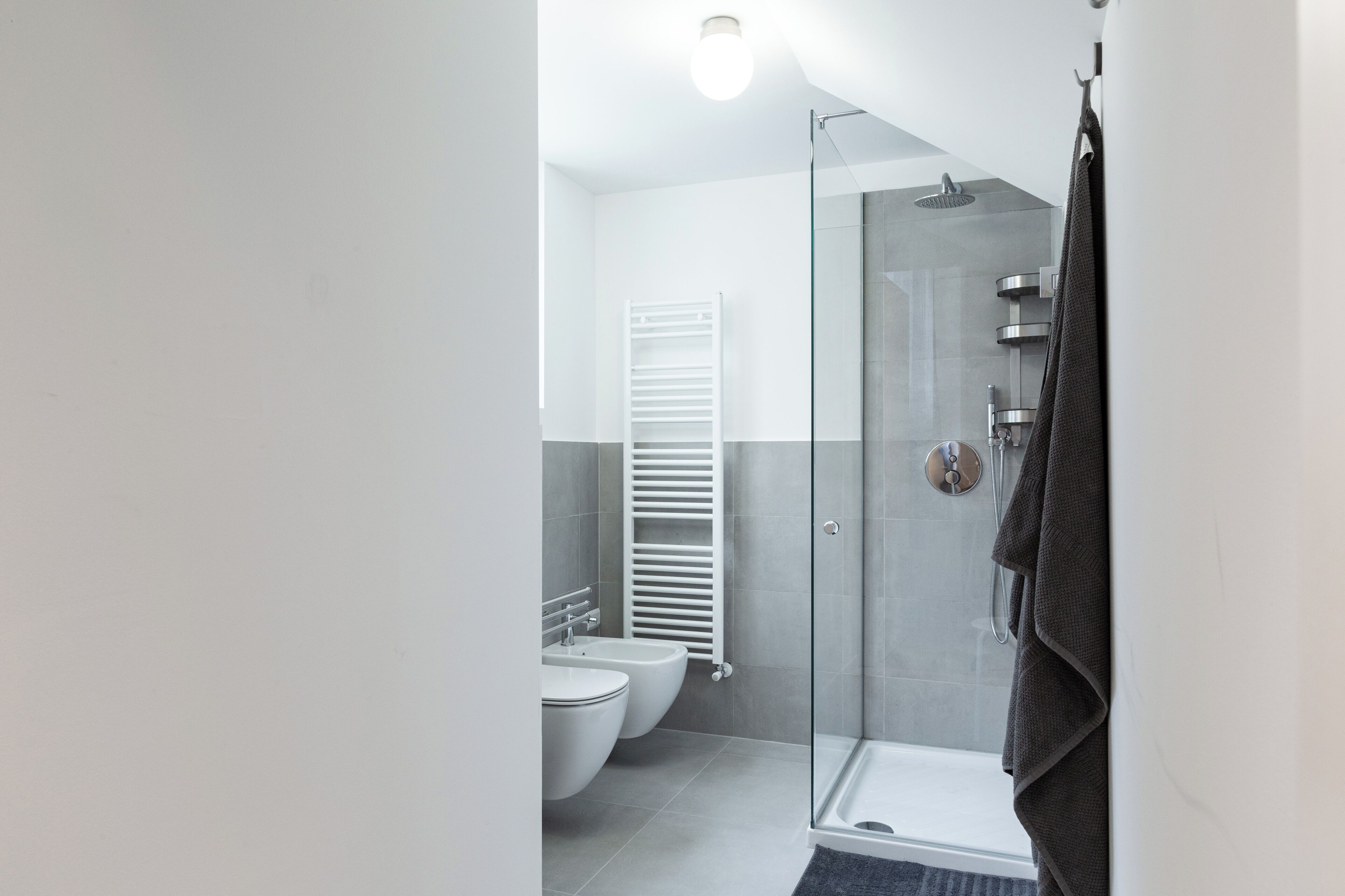 Une salle de bain moderne avec une douche à parois de verre, un porte-serviettes blanc et une serviette blanche accrochée au mur.