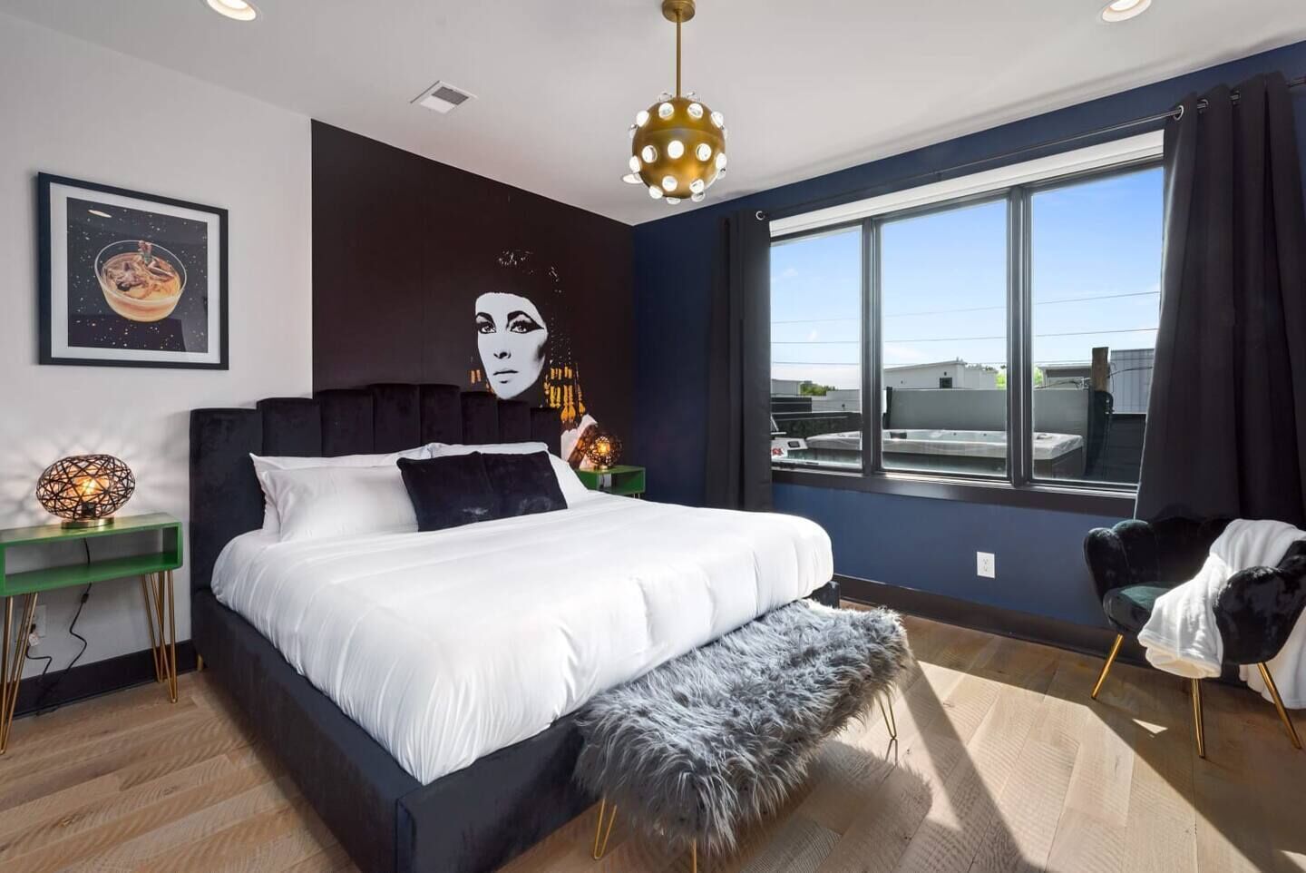 Ein modernes Schlafzimmer mit einem großen Bett, Blick zum Himmel durch ein Fenster und einem einzigartigen Wandkunstwerk.