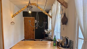 A wooden dining table with chairs, a chandelier, and a kettle on the table. - Hnameni Stepanavan Guesthouse (Step'anavan)