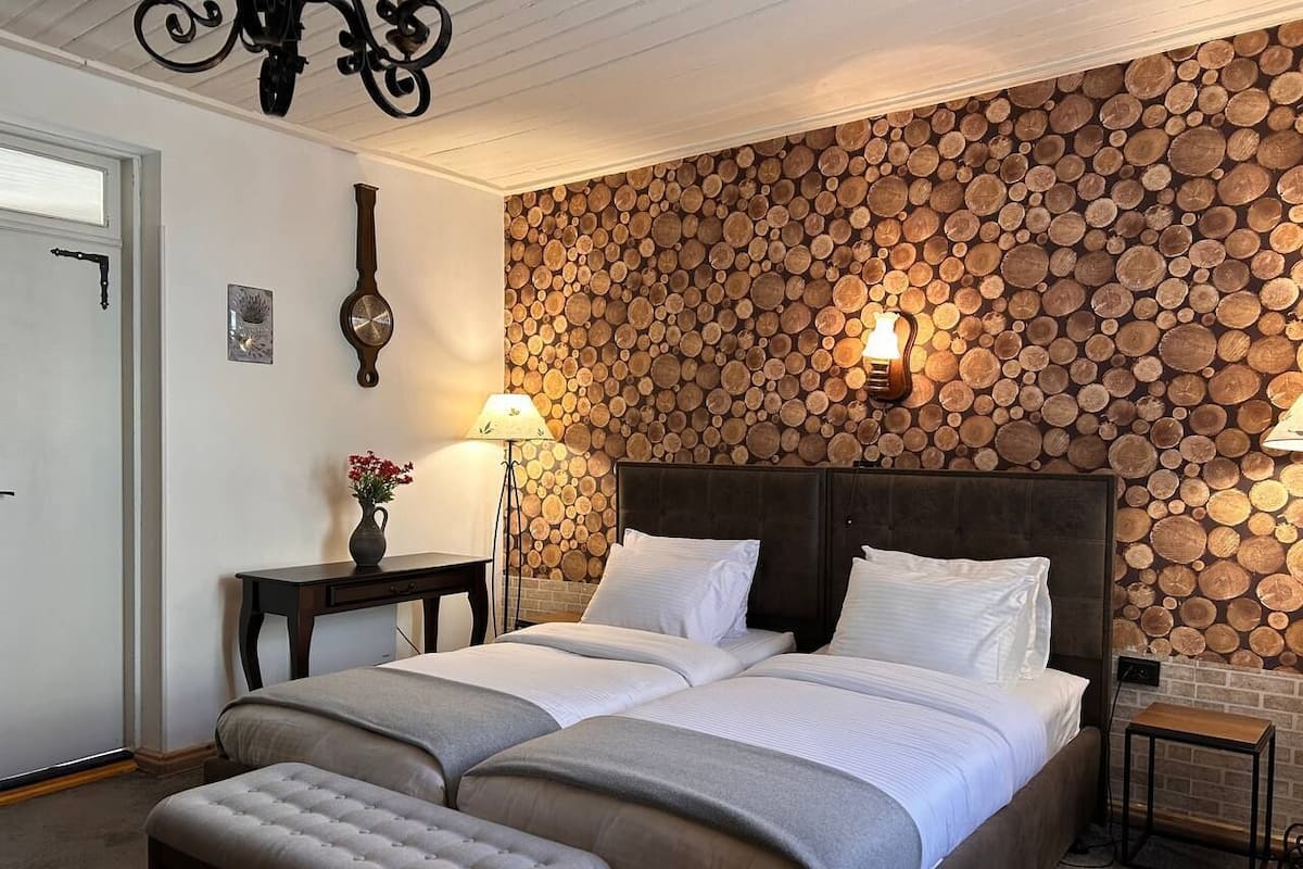 Un dormitorio con una cama grande, una mesita de noche, una lámpara y una pared revestida de troncos.