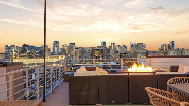 Une terrasse sur le toit agrémentée d’un foyer, de meubles en osier et offrant une vue panoramique sur la ville.