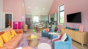 Una sala de estar moderna con un sofá, sillas, una mesa de centro y un televisor.