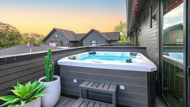 Una azotea con un jacuzzi, una planta en maceta y una terraza de madera.