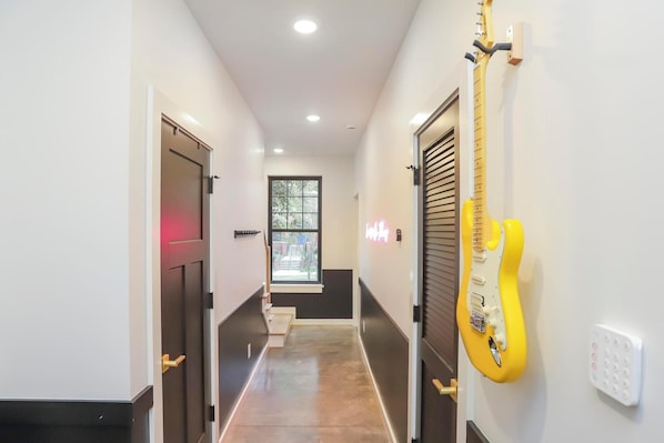 A hallway with a yellow guitar, a window, and a door.