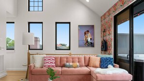 Ein modernes Wohnzimmer mit einem rosa modularen Sofa, einem runden Couchtisch und einem großen Fenster mit Blick.
