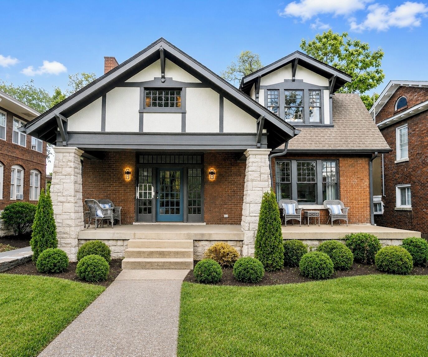A two-story house with a front porch, a brick facade, and a well-maintained lawn.