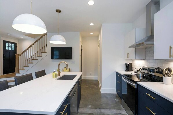 A modern kitchen with a large island, dark cabinetry, and stainless steel appliances.