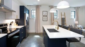 A modern kitchen with a central island, stainless steel appliances, and pendant lighting. - Chic Belmont Retreat | Walk to Hillsboro & 12 South (Nashville)