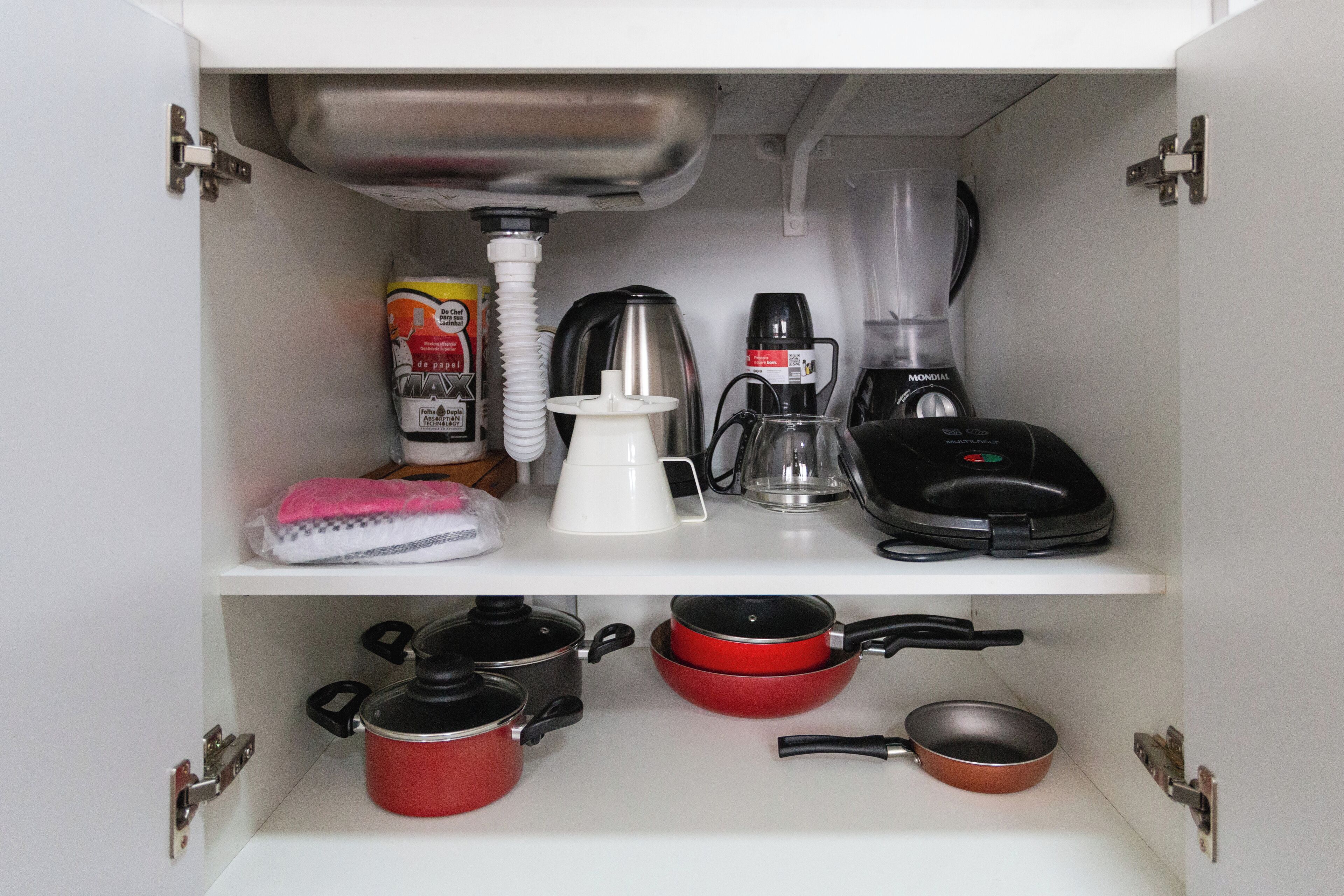 A kitchen cabinet with a built-in sink, a coffee maker, a blender, and various pots and pans.