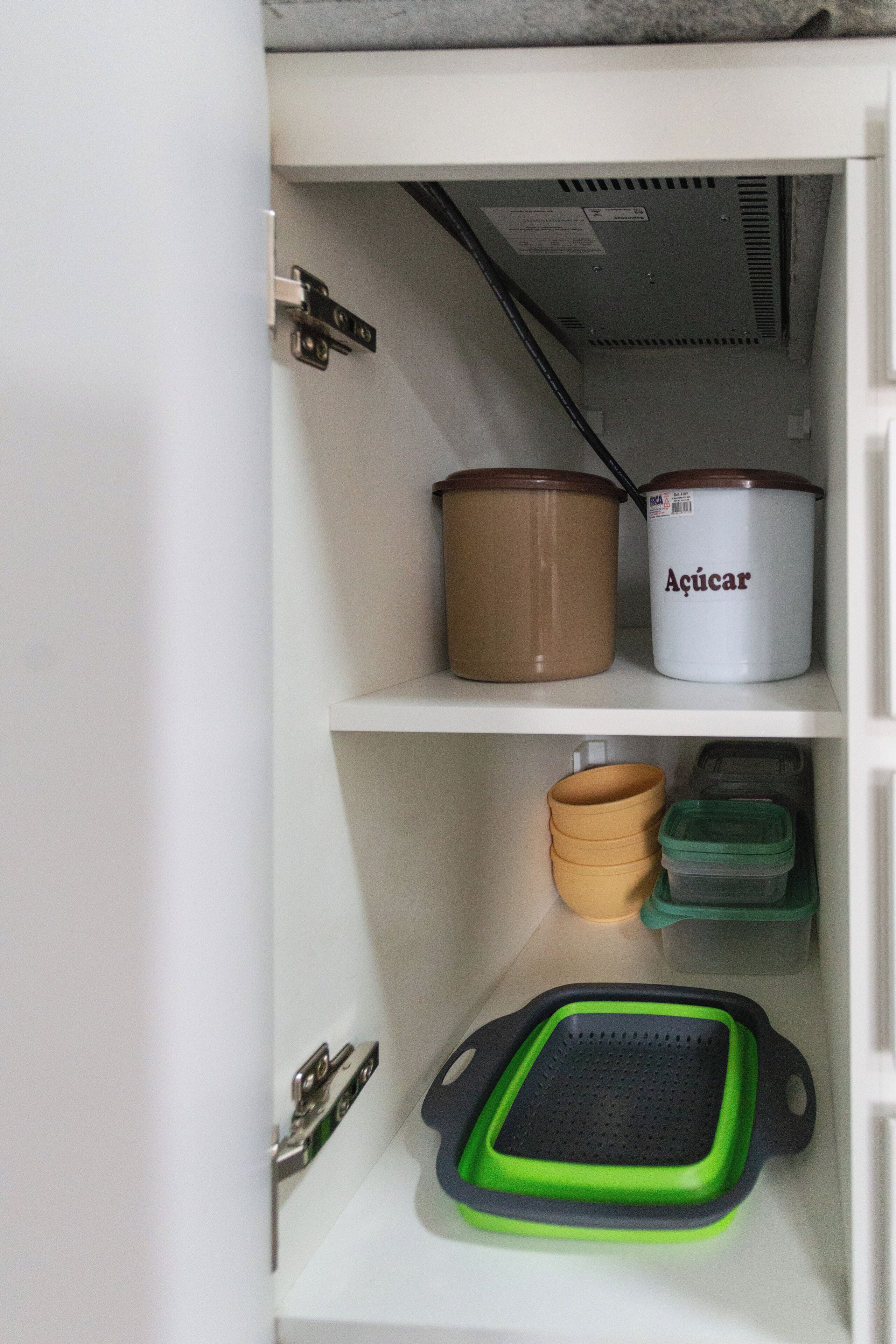 Een voorraadkast in de keuken met opbergcontainers en een groene dienblad.