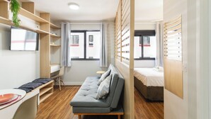 Una camera d'albergo compatta con un divano, un letto, una scrivania e una televisione.