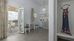 Ein modernes Zimmer mit einer Schiebetür zum Balkon, einer kleinen Essecke und einer Küchenzeile.
