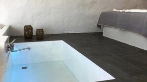 Ein modernes Badezimmer mit freistehender Badewanne, dunklem Fliesenboden und einer weißen Wand.