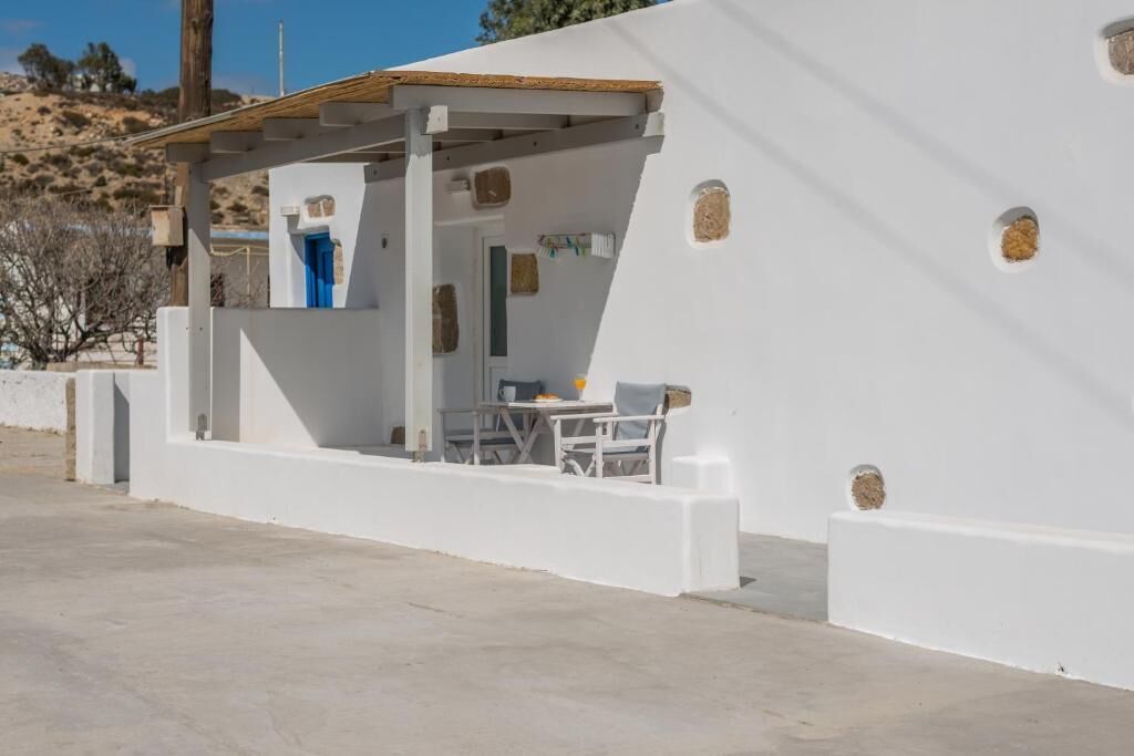 Un edificio blanco con un espacio de estar al aire libre cubierto y una puerta azul.