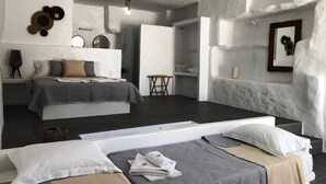 Ein modernes Schlafzimmer mit einem großen Bett, einem kleineren Bett und einer Sitzecke mit einer Bank.