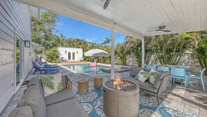 Un espacio al aire libre techado con piscina, mobiliario y una chimenea.