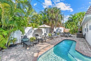 A backyard with a swimming pool, lounge chairs, and a pergola.