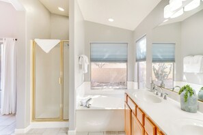 Enjoy a refreshing shower or soak in the standalone bathtub in this well-lit bathroom with a double sink.