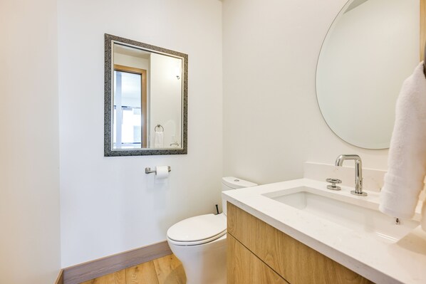 A bathroom with a toilet, a sink, a mirror, and a towel hanging on the wall.