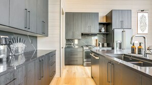 A modern kitchen with grey cabinets, stainless steel appliances, and a wooden floor. - Modern Ski-in/out Home in Brian Head w/ Deck (Brian Head)