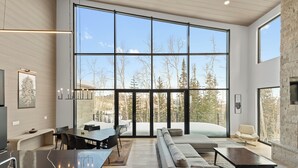 A modern living room with a large window, a fireplace, and a stone wall. - Modern Ski-in/out Home in Brian Head w/ Deck (Brian Head)