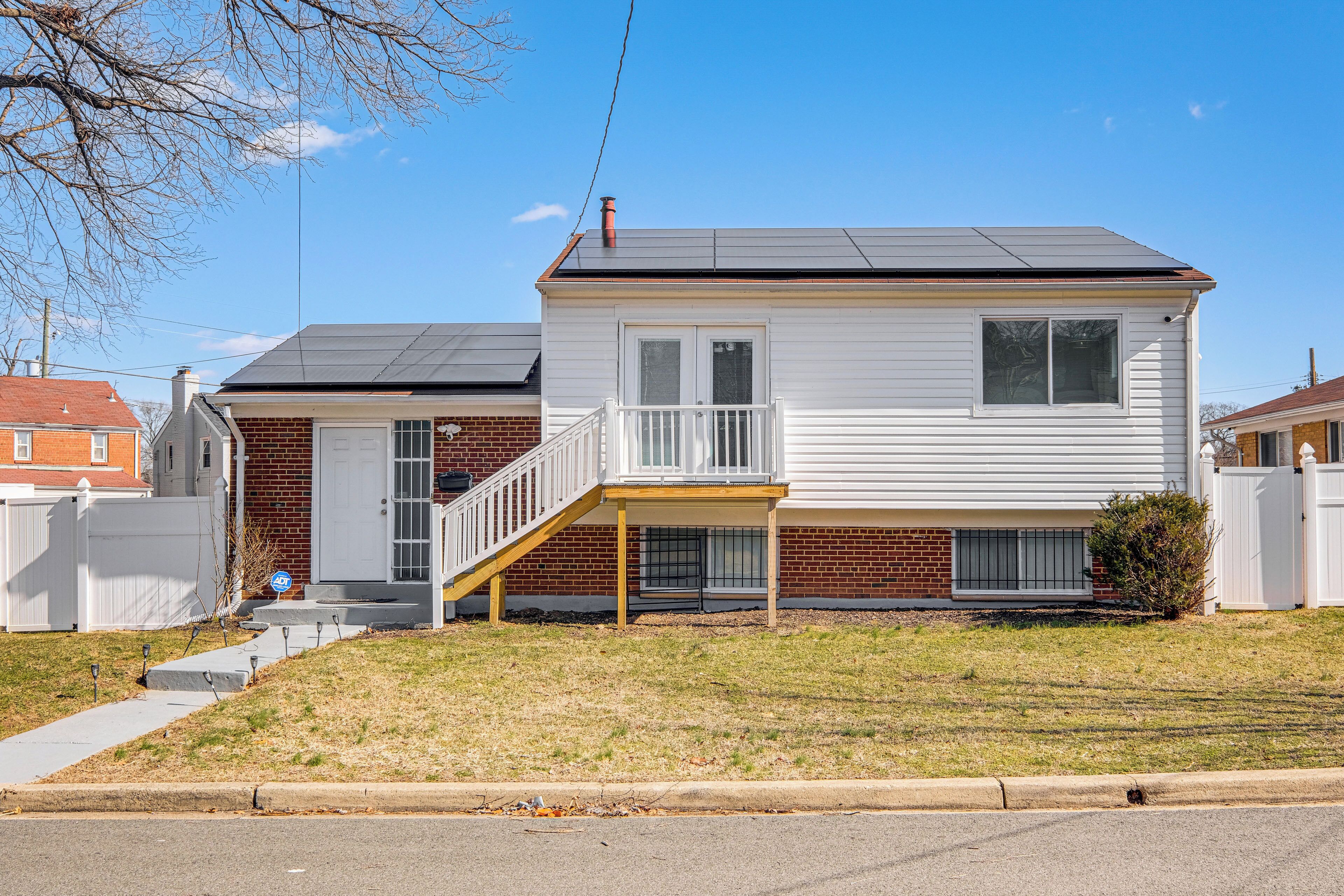 A two-story house with a front porch, a brick foundation, and a metal roof.