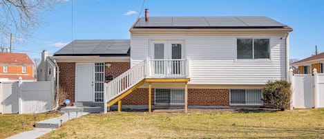 A two-story house with a front porch, a brick foundation, and a metal roof.