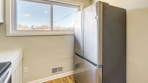 Una cocina con un refrigerador de acero inoxidable, una ventana que ofrece vistas al exterior y una encimera blanca.