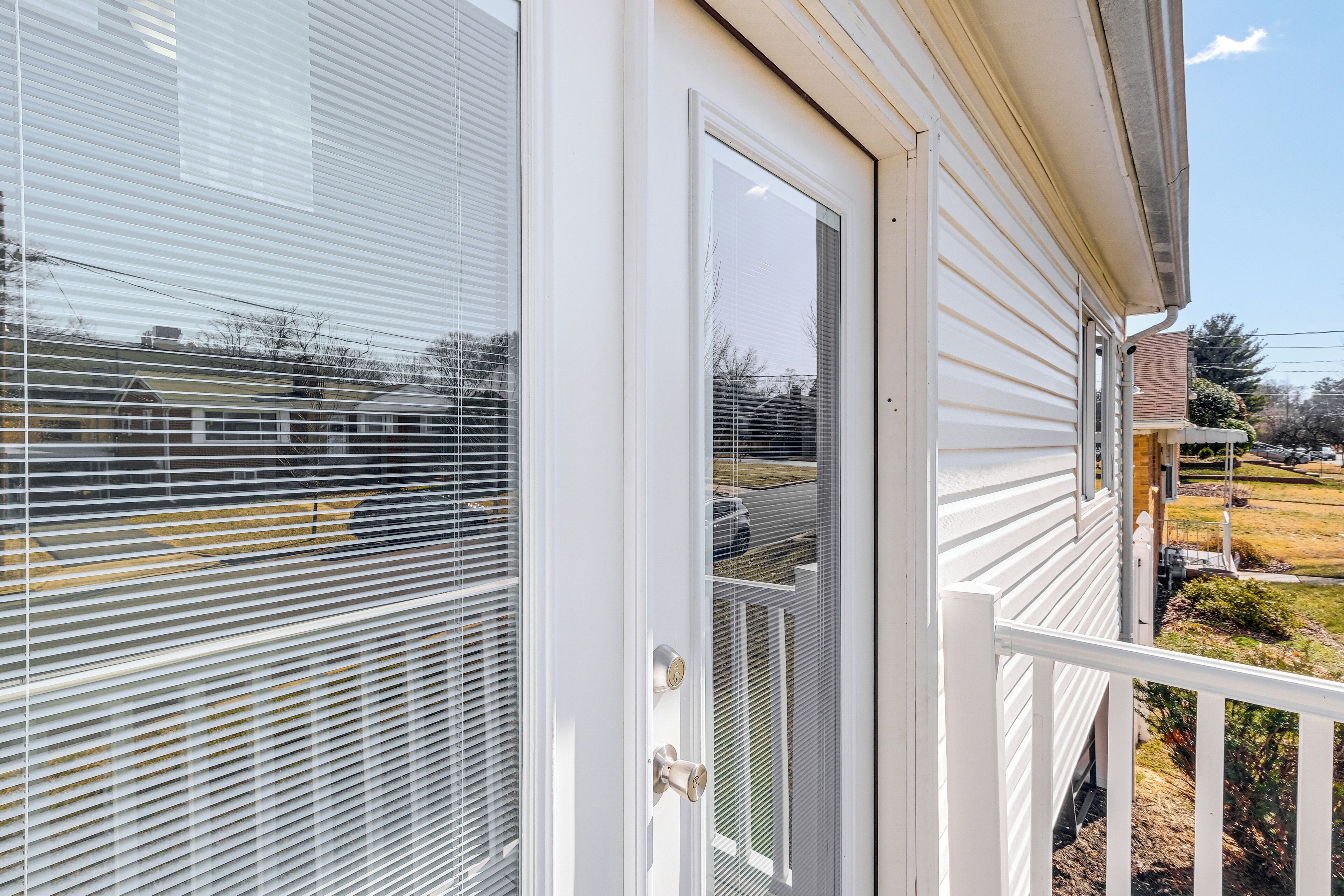 A white house with a sliding glass door and a small porch with a railing.