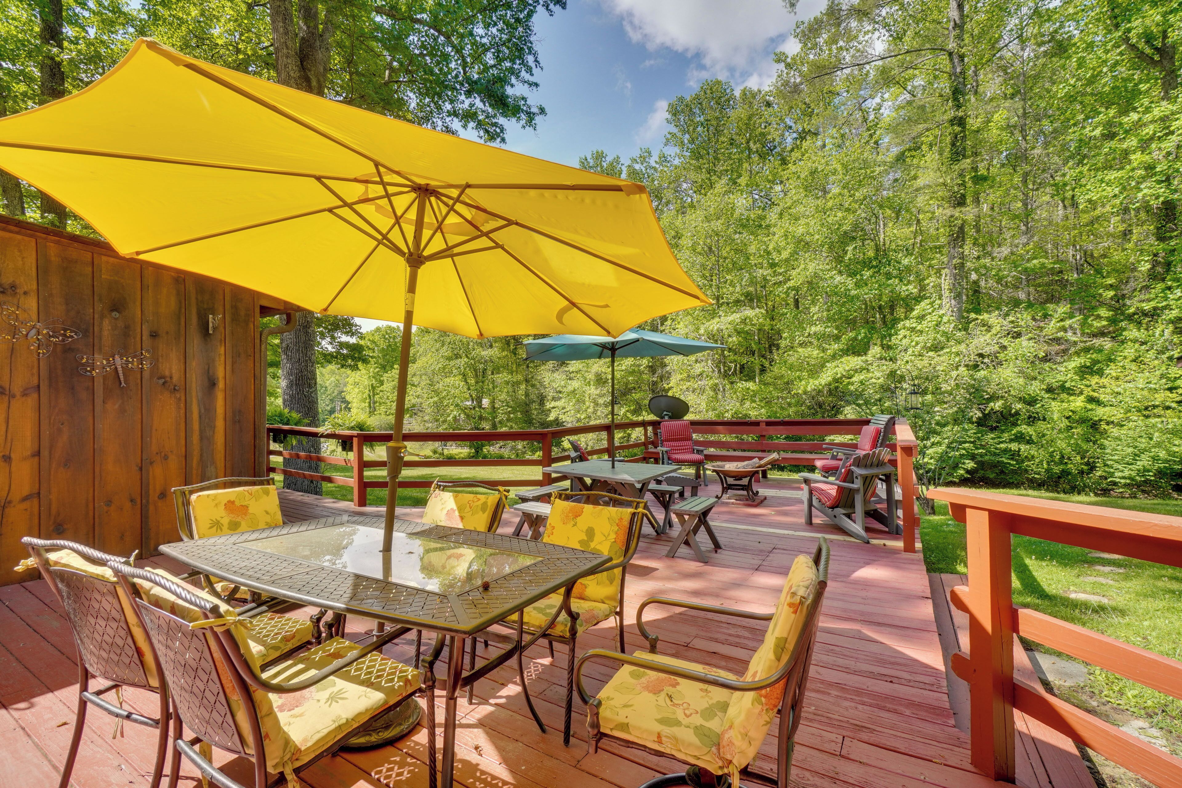 A wooden deck with outdoor furniture, including tables and chairs, and a yellow umbrella.