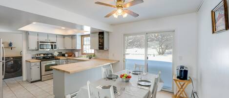 A modern kitchen with a central island, stainless steel appliances, and a dining area with a table set for four.