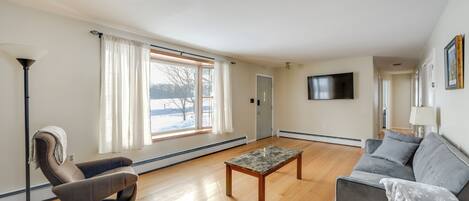 A living room with a sofa, a massage chair, a coffee table, and a TV mounted on the wall.
